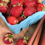strawberries in a container with rhubarb next to it