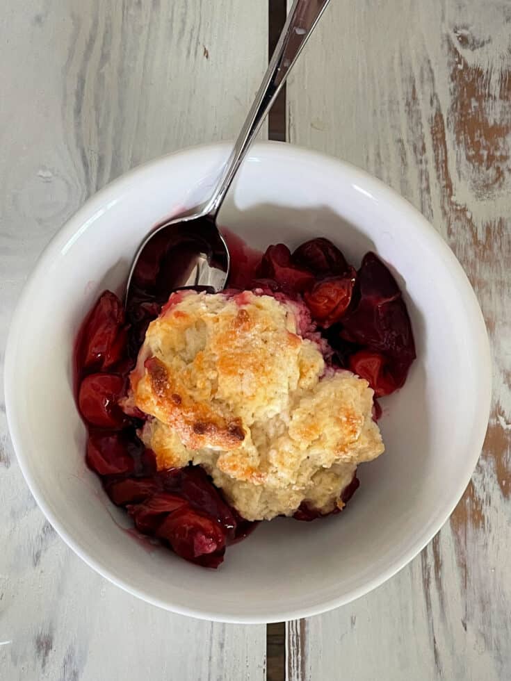 homemade sour cherry cobbler in a bowl with a spoon